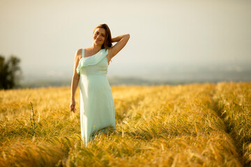 Young pregnant woman in white dress relaxing outside in nature