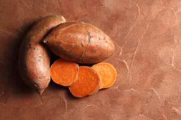 Composition of Fresh ripe sweet potatoes, on a colored table background