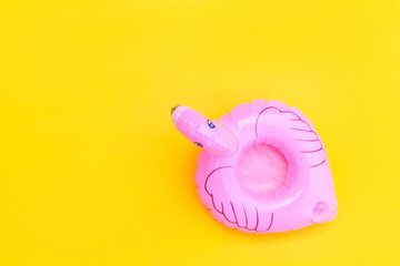 Summer beach composition. Simply minimal design with pink Inflatable flamingo isolated on yellow background. Pool float party, trendy celebrity fashion concept. Flat lay top view copy space.