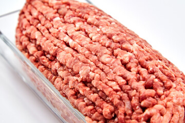 Fresh minced meat close-up in a glass dish plate. Isolated on a white background.