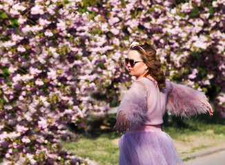 the girl is standing under the pink tree that bloom