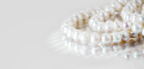 A necklace of white pearls on a glass surface with a place for text.