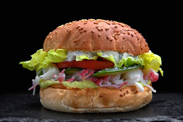 Burger, hamburger with crab sticks, crab meat, cucumber, tomato, lettuce, sauce, on a black background