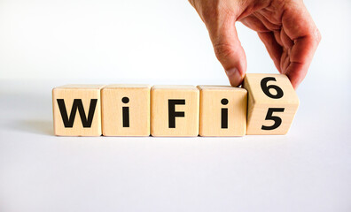 WiFi 5 or 6 symbol. Businessman turns a wooden cube and changes the words WiFi 5 to WiFi 6. Beautiful white background, copy space. Business, technology and WiFi 5 to WiFi 6 concept.