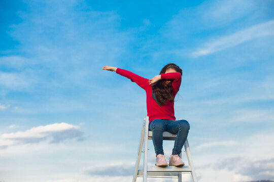 The girl is sitting on top of a ladder on the sky