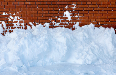 Snow removal  against a brick wall.