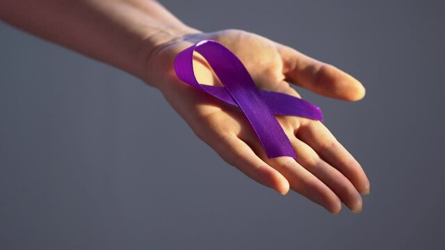 Hands holding purple ribbons, toning copy background, Alzheimer's disease, pancreatic cancer, epilepsy awareness, domestic violence awareness, fibromyalgia awareness, world cancer day