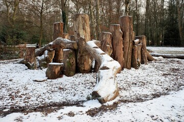 Natural woodland play area made with sustainably felled oak tree trunks in winter snow
