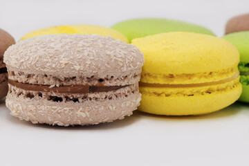 Chocolate macaroni sprinkled with coconut. White background, horizontal photo. Delicious, French sweets.
