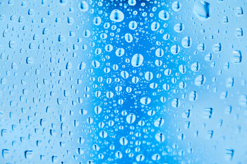 Cool water and water drops on a blue plastic bottle . Selective focus. Closeup