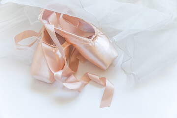 New pastel beige ballet shoes with satin ribbon and tutut skirt isolated on white background. Ballerina classical pointe shoes for dance training. Ballet school concept. Top view flat lay, copy space