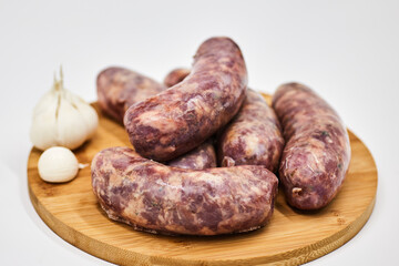 Raw sausage semi-finished products lie on a wooden board, isolated on a white background. The concept of cooking from semi-finished products. Italian traditions, Bavarian sausages, German sausages