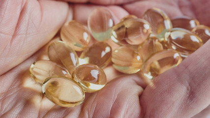capsules with omega 3  lie on man's wrinkled palm, macro