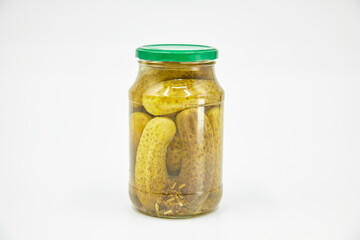 Canned vegetables. Large green cucumbers in brine in a jar with spices, isolated on a white background.