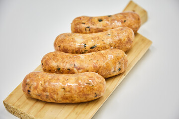 Raw sausages lie on a wooden Board, isolated on a white background. The concept of cooking food from semi-finished products. Italian traditions, Bavarian sausages