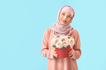 Beautiful mature Muslim woman with flowers on color background. International Women's Day celebration