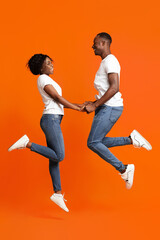 Fototapeta na wymiar Romantic black couple in love holding hands and jumping up
