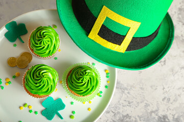 Dessert stand with tasty cupcakes for St. Patrick's Day and leprechaun hat on grunge background