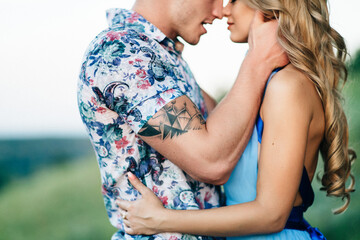 Fototapeta premium blonde girl with loose hair in a light blue dress and a guy in the light of sunset