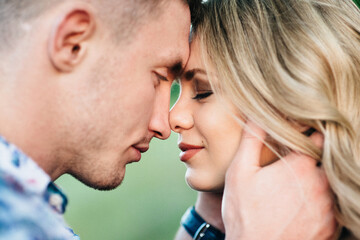 blonde girl with loose hair in a light blue dress and a guy in the light of sunset