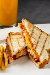 Toast with cheese, egg and Turkish sausage served with salad and french fries on white plate