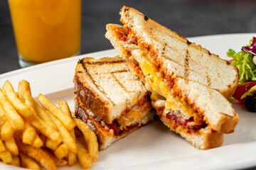 Toast with cheese, egg and Turkish sausage served with salad and french fries on white plate