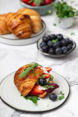 Croissant sandwich with cheese , arugula and berries.