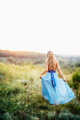 blonde girl with loose hair in a light blue dress and a guy in the light of sunset