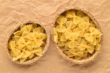 Light yellow butterfly paste in two straw plates on brown paper, close-up, top view.