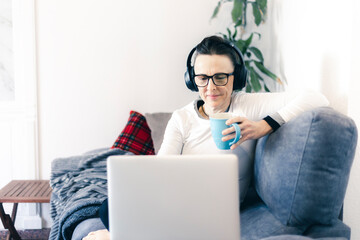 woman working on the sofa with laptop and headphones