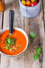 Tomato cream soup with basil pesto on wooden table