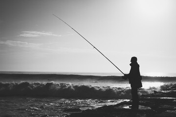 Fisherman on a pier with angry sea black and white