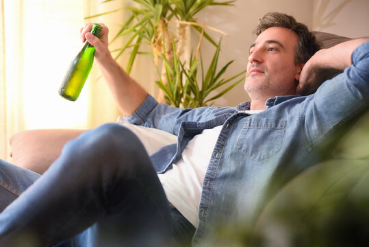 Relaxed Man With A Beer Sitting On A Sofa Comfortably