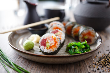 Sushi maki rolls with tuna, flying fish caviar, crab, avocado on a plate with chopsticks, soy sauce, wasabi and ginger. Japanese traditional food closeup served for lunch in modern gourmet restaurant