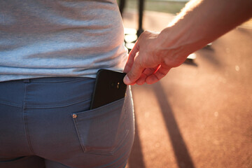 Close-up of a man is hand steals a mobile phone with a jeans pocket. Crime, pickpocketing on the...