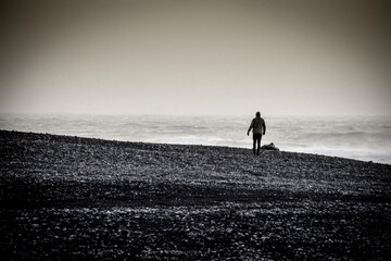 lonely person on a black sand beach in a stormy day