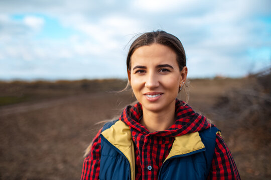Outdoor portrait of young smiling girl on blurred background of sky and field.