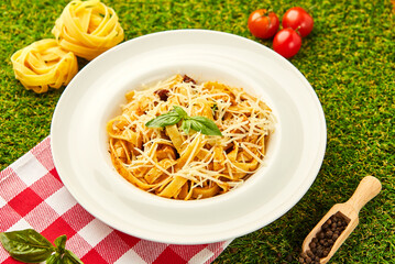 Spaghetti pasta with pesto sauce and sun-dried tomatoes served in a plate with parmesan cheese and basil