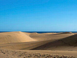 Fototapeta na wymiar View of the Natural Reserve of Dunes of Maspalomas, golden sand dunes, blue sky. Gran Canaria, Canary Islands, Spain