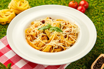 Spaghetti pasta with pesto sauce and sun-dried tomatoes served in a plate with parmesan cheese and basil