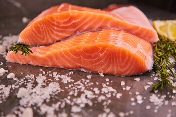 Fresh raw fillet of sea fish salmon or trout with spices and herbs on a dark background. The concept of cooking fresh fish in a restaurant or at home in the kitchen