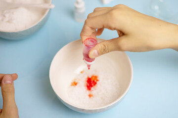 a child makes a bath bomb from sea salt, citric acid, soda, dye and flavor on a blue background, instructions, step 2