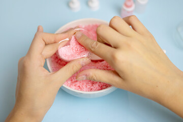 a child makes a bath bomb from sea salt, citric acid, soda, dye and flavor on a blue background,...