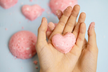 a child makes a bath bomb from sea salt, citric acid, soda, dye and flavor on a blue background,...