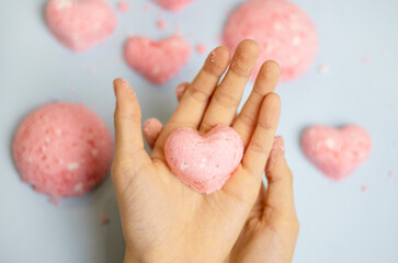 a child makes a bath bomb from sea salt, citric acid, soda, dye and flavor on a blue background,...