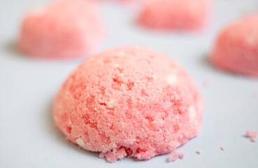 selective focus of a bath bomb from sea salt, citric acid, soda, dye and flavor on a blue background