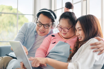 Happy asian family with their daughter down syndrome child sitting on sofa  have fun using laptop...