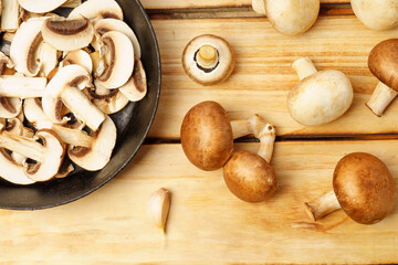 Sliced mushrooms in a frying pan, porcini and royal champignons on a wooden