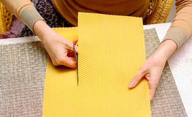Making a candle from a plate of beeswax. DIY wax candle making process. Natural candles fragrant with honey will be made from these sheets. Step 1. Cutting the wax plate into pieces.