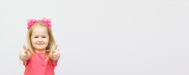 Happy little girl showing a thumbs up sign or OK symbol. Isolated on white background